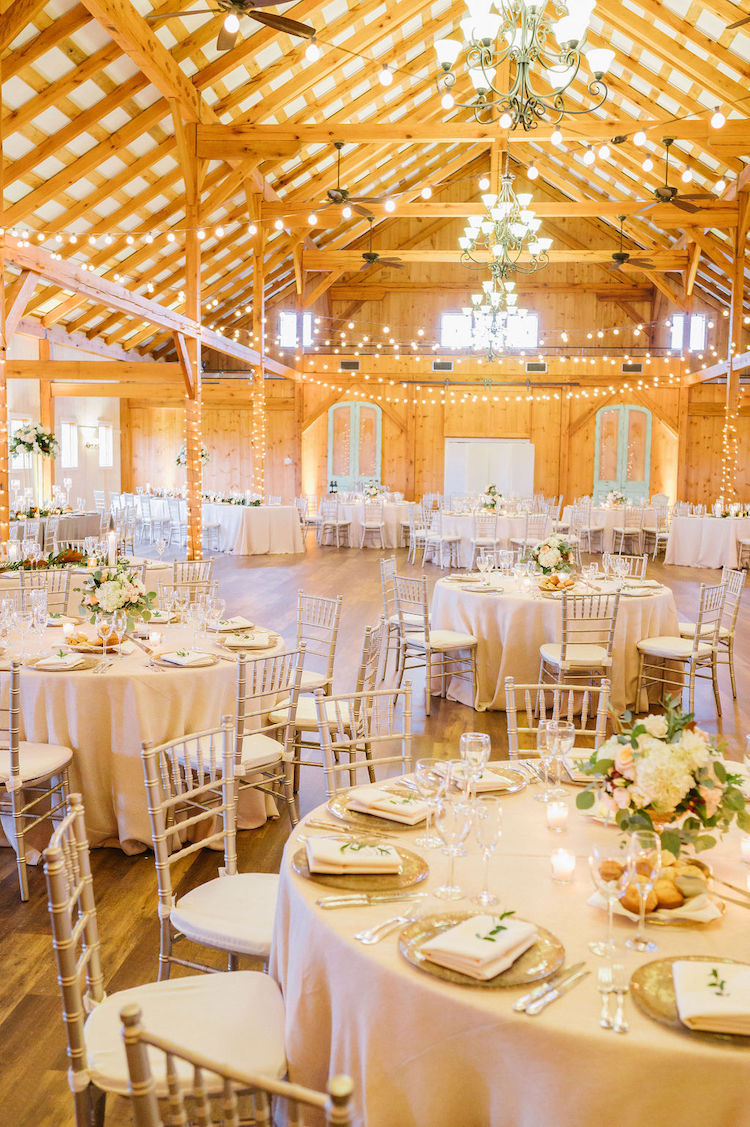 light, bright barn reception setup with beige round tables and silver chairs neutral wedding - Loudoun County wedding Lisa Havard Events